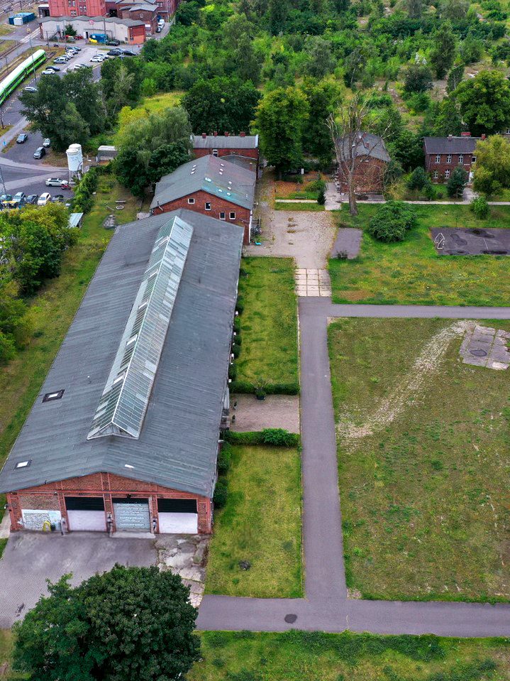 Luftaufnahme des Cordeshofs: die lange Backsteinhalle mit Glasdach, der Hof, die Wiese mit Betonplatten und die alten Backsteinhäuser im Grünen